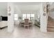 Bright, open-concept dining area with light wood floors, neutral decor, and staircase access at 13556 Abberwick Dr, Orlando, FL 32832