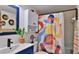 A bathroom with a trendy blue vanity, stylish mirror, colorful shower curtain, and updated fixtures to create a relaxing haven at 145 N Halifax Ave # 705, Daytona Beach, FL 32118