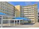 Harborview building with balconies and covered parking with blue canvas, set against a clear blue sky at 145 N Halifax Ave # 705, Daytona Beach, FL 32118