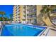 Community pool with clear blue water, surrounded by a fence, palm trees, and an inviting space for relaxation and recreation at 145 N Halifax Ave # 705, Daytona Beach, FL 32118
