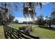 Outdoor community tennis court with green space, shade trees, and wooden fence at 2043 Town Pasture Dr, Eustis, FL 32726