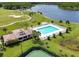 Aerial view of a community pool with lounge seating and nearby clubhouse, adjacent to a scenic lake at 219 Isle Of Sky Cir, Orlando, FL 32828