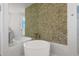 Modern bathroom featuring a soaking tub, stone accent wall, and sleek fixtures at 219 Isle Of Sky Cir, Orlando, FL 32828