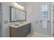 This bathroom features a gray vanity with ample storage space, a large mirror, and a window with natural light at 219 Isle Of Sky Cir, Orlando, FL 32828