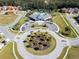 Community clubhouse featuring a circular driveway with palm trees, manicured landscaping, and beautiful trees at 2515 Dharma Cir, Kissimmee, FL 34746