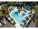 Aerial view of resort-style pool with sun loungers, palm trees, shade umbrellas, and beautifully landscaped grounds at 2515 Dharma Cir, Kissimmee, FL 34746
