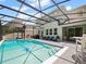 Backyard pool with a screened-in enclosure, a patio area with outdoor furniture, and a grill at 2621 Peony Dr, Oviedo, FL 32766