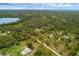 This aerial perspective features a charming home with a pool surrounded by the lake and forest at 2630 S Tanner Rd, Orlando, FL 32820