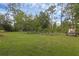Expansive backyard featuring lush green lawn, mature trees, and a charming garden area, creating a serene outdoor space at 2630 S Tanner Rd, Orlando, FL 32820