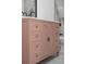 Elegant pink bathroom vanity featuring sleek lines, modern gold hardware, and ample storage, adding a pop of color at 2639 Monaco Cove Cir, Orlando, FL 32825