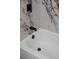 Close up of a bathtub with modern black fixtures and marble tile at 2639 Monaco Cove Cir, Orlando, FL 32825