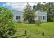 Lush backyard with green grass and mature trees surrounding a single-story home at 302 E Oakland Ave, Oakland, FL 34760
