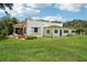 Back exterior view of the house showing an overgrown lawn and outdated windows at 302 E Oakland Ave, Oakland, FL 34760