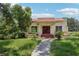 Charming home featuring a red-tiled roof, red front doors, and mature landscaping at 302 E Oakland Ave, Oakland, FL 34760