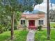 Inviting home featuring a vibrant red door, red accents and a well-manicured lawn at 302 E Oakland Ave, Oakland, FL 34760