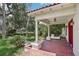 Front porch with red flooring and white columns, set amidst mature landscaping at 302 E Oakland Ave, Oakland, FL 34760