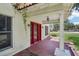 Front porch featuring red flooring, white columns, and a red front door at 302 E Oakland Ave, Oakland, FL 34760