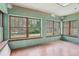 Empty living room with original wood windows looking out onto a large yard and hardwood floors at 302 E Oakland Ave, Oakland, FL 34760