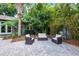 Lush backyard with patio furniture, brick pavers, mature trees, and tropical landscaping at 3601 S Summerlin Ave, Orlando, FL 32806