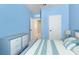 Stylishly decorated bedroom with blue walls, striped bedding and an open doorway at 410 Winter Bliss Ln, Mount Dora, FL 32757