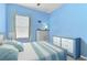 Bright blue bedroom with a comfortable bed, window, dresser, and decor at 410 Winter Bliss Ln, Mount Dora, FL 32757