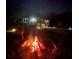 Nighttime shot of a roaring backyard fire pit with modern home in the background at 610 Cypress Ave, Orange City, FL 32763