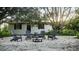 Charming outdoor stone patio with gray chairs and a fire pit, under a mature tree at 610 Cypress Ave, Orange City, FL 32763