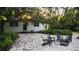 Charming outdoor stone patio with gray chairs and a fire pit under a mature tree at 610 Cypress Ave, Orange City, FL 32763