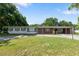 Ranch-style home featuring a brick facade, long driveway, covered parking, and mature trees against a blue sky at 622 Avenue D Se, Winter Haven, FL 33880