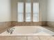 Bathroom featuring a large soaking tub below three large windows for natural light at 6971 Tettenhall Ln, Windermere, FL 34786