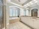 Bathroom featuring double sink vanity, tiled floors, bathtub and glass door shower at 6971 Tettenhall Ln, Windermere, FL 34786