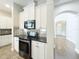 Bright kitchen boasts stainless steel appliances, tiled backsplash, white cabinets, and an easy flow into the entry way at 6971 Tettenhall Ln, Windermere, FL 34786