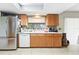 A well-lit kitchen with stainless steel refrigerator, wooden cabinets, and a view of the backyard at 7022 Talbot Dr, Orlando, FL 32819
