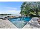 Beautiful pool overlooking the serene lake, surrounded by lush greenery and stylish stone pavers at 7801 Georgeann St, Winter Park, FL 32792