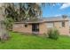 A view of the backyard featuring a lush lawn, mature trees, and a neutral-tone brick exterior at 8111 Esperanza St, Orlando, FL 32817