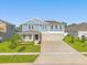 Two-story home featuring a 3-car garage, blue siding, and manicured lawn at 9535 Beautiful Way, Winter Garden, FL 34787