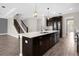 Island kitchen boasts stainless appliances, dark cabinetry and quartz countertops with pendant lighting and tile floors at 9535 Beautiful Way, Winter Garden, FL 34787