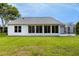 The back exterior of a home with a screened lanai and a spacious green lawn at 956 Chula Ct, Lady Lake, FL 32159