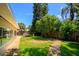 Green backyard and patio with walkway, lush tropical trees, and wood fence at 105 John Anderson Dr, Ormond Beach, FL 32176