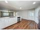Bright kitchen with white cabinets and stainless appliances overlooks living area with wood floors at 117 Burns Ave, Longwood, FL 32750