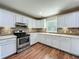 Kitchen featuring white cabinets, stainless appliances, and tiled backsplash over wood floors at 117 Burns Ave, Longwood, FL 32750
