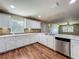 Bright kitchen features white cabinets and stainless steel appliances over wood floors at 117 Burns Ave, Longwood, FL 32750