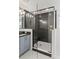 Modern bathroom features an oversized glass enclosed shower with black tile and white accents at 12468 Koshiba Aly, Orlando, FL 32827