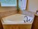 Bathroom with a corner soaking tub, tiled surround, granite counters, and a large window at 12832 Sawgrass Pine Cir, Orlando, FL 32824