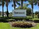 Landscaped Sawgrass community sign featuring flowers, shrubs, and palm trees under a sunny sky at 12832 Sawgrass Pine Cir, Orlando, FL 32824