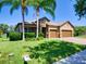 Beautifully landscaped front yard featuring palm trees and a brick driveway leading to the three-car garage at 12832 Sawgrass Pine Cir, Orlando, FL 32824