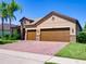 Exterior showcasing a well-maintained two-car garage home with brick-paved driveway at 12832 Sawgrass Pine Cir, Orlando, FL 32824