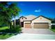 Charming single-Gathering home showcasing a three-car garage, manicured lawn, and beautiful landscaping at 12832 Sawgrass Pine Cir, Orlando, FL 32824