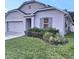 Single-story home with a well-manicured lawn and gray exterior with clean lines in a sunny neighborhood at 1588 Diamond Loop Drive, Kissimmee, FL 34744