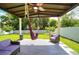 Inviting covered patio with ceiling fan, hammock, wicker furniture and lush lawn at 1588 Diamond Loop Drive, Kissimmee, FL 34744
